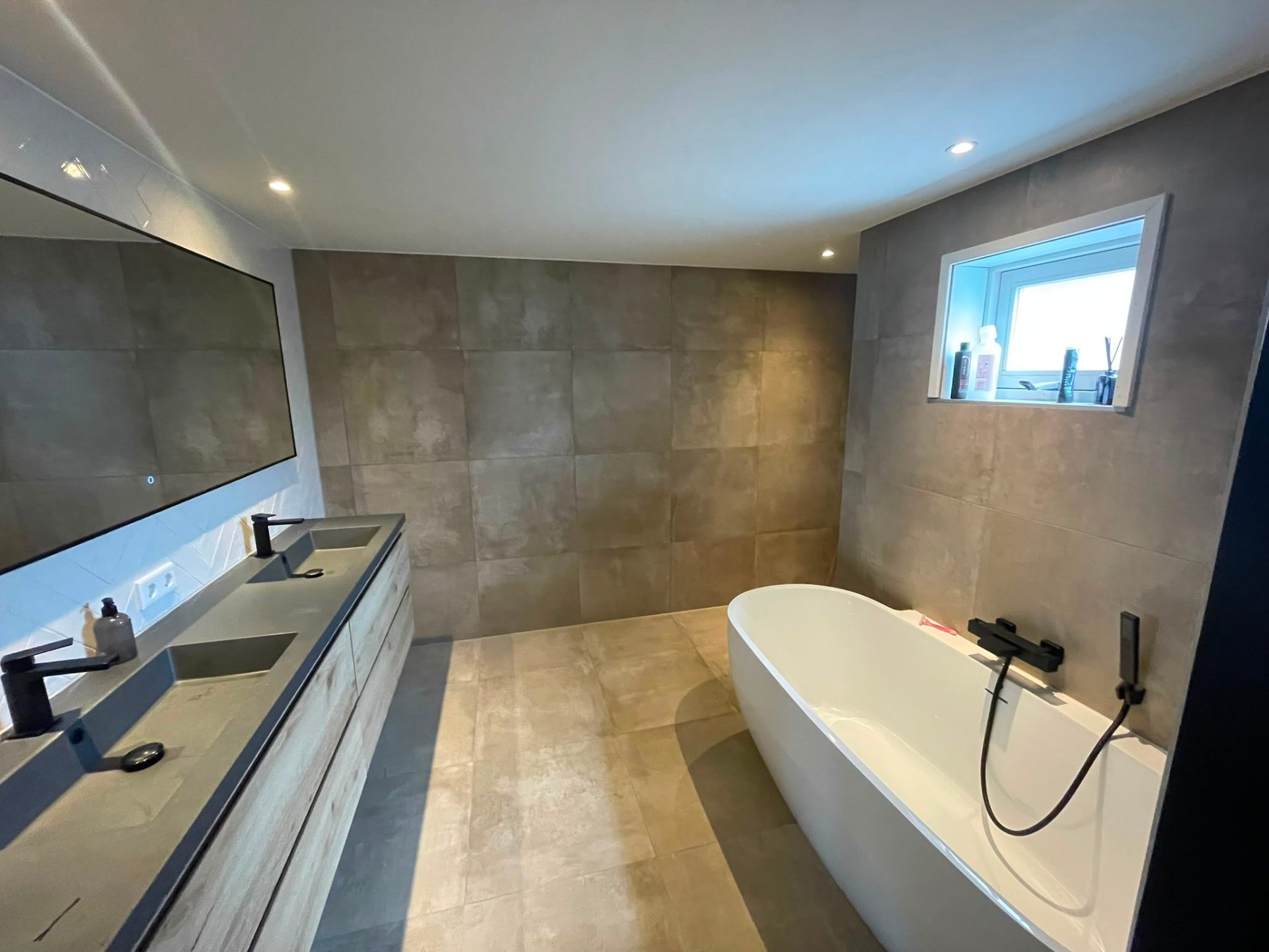 Tegelwerk — moderne badkamer met betonlook tegels en vrijstaand bad